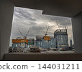 A panoramic view of a massive modern commercial complex under construction along Rama III Road, dramatically framed through a geometric concrete window opening. 144031211