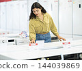 Woman is shopping in a store - choosing washing machine 144039869