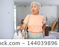 Surprised mature woman in apartment during overhaul 144039896