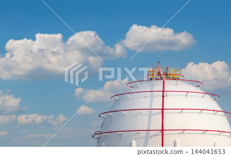 Spherical gas storage tank on the right beneath a blue sky and white clouds at a petrochemical facility in daylight, with broad copy space for energy supply and industrial fuel storage communications Spherical gas storage tank on the right beneath a blue sky and white clouds at a petrochemical facility in daylight, with broad copy space for energy supply and industrial fuel storage communications 144041653