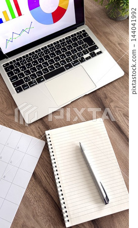 A computer and calendar set in a vertical orientation, representing data analysis and schedule management. A computer and calendar set in a vertical orientation, representing data analysis and schedule management. 144041992